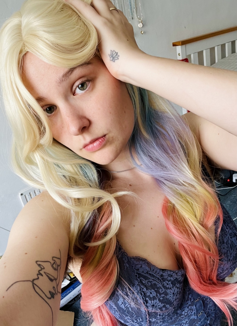 This multi-colour wig is a mixture of purple, blues, limes, greens and peach. From the nape of the neck giving a peek-a-boo effect. A natural blonde colour from the roots, thats carried into the sleek blunt fringe. Long and curly with invisible layers for bounce and volume.