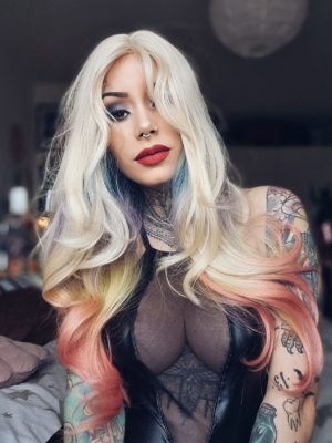 This multi-colour wig is a mixture of purple, blues, limes, greens and peach. From the nape of the neck giving a peek-a-boo effect. A natural blonde colour from the roots, thats carried into the sleek blunt fringe. Long and curly with invisible layers for bounce and volume.