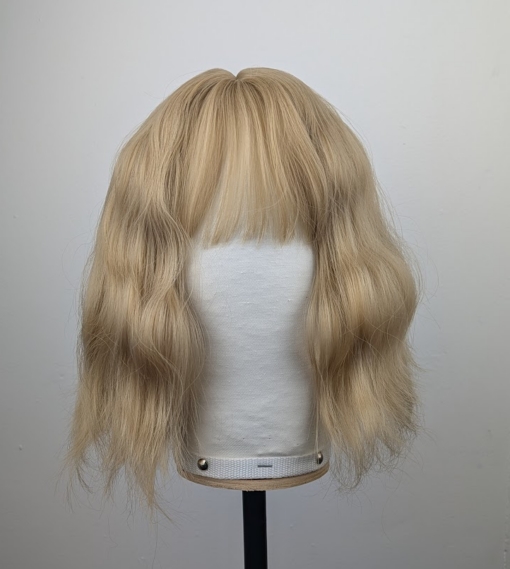 This bob has very loose tousled waves. A light blonde shade from roots to tips. With a sleek blunt fringe.