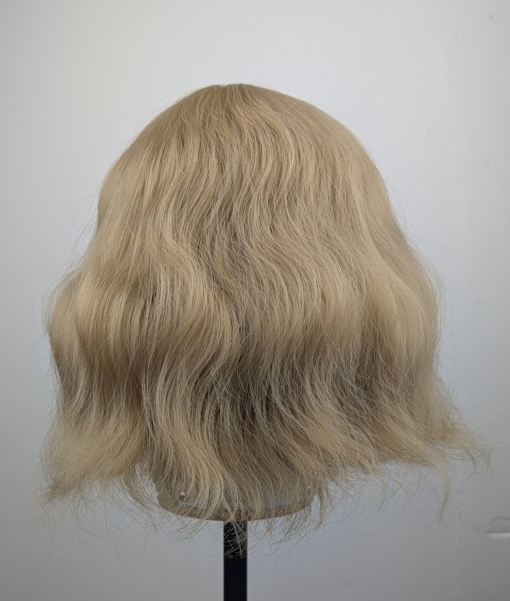 This bob has very loose tousled waves. A light blonde shade from roots to tips. With a sleek blunt fringe.