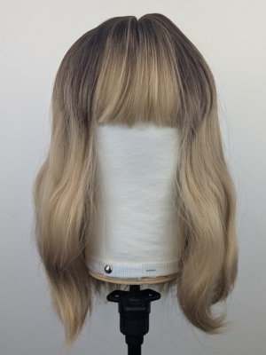 A long bob coloured in a honey blonde tone with brown shadowed roots for a completely natural feel. Finished with loose waves and a sleek fringe.