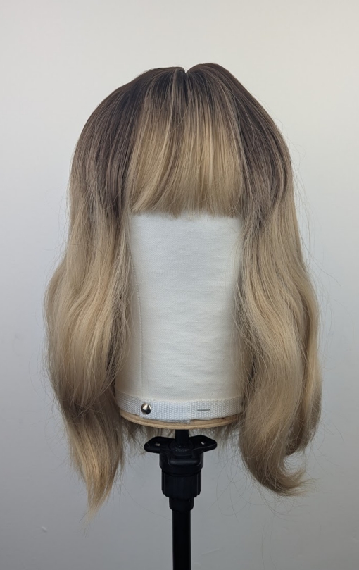 A long bob coloured in a honey blonde tone with brown shadowed roots for a completely natural feel. Finished with loose waves and a sleek fringe.