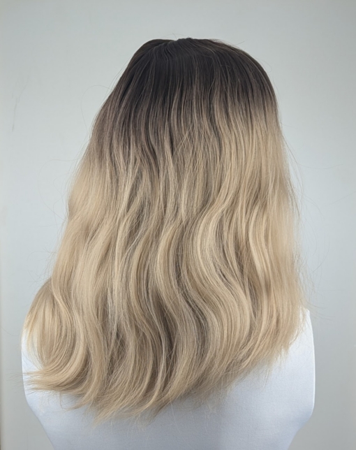 Eleri - Lush Wigs UK This long bob with dark brown shadow roots blend into a warm blonde hue. Styled in a loose wave with a sleek blunt fringe.