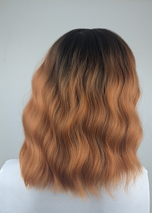 Embers - Lush Wigs UK A dark apricot wig with brown shadowed roots. Styled into a bob with loose waves and a sleek blunt fringe.