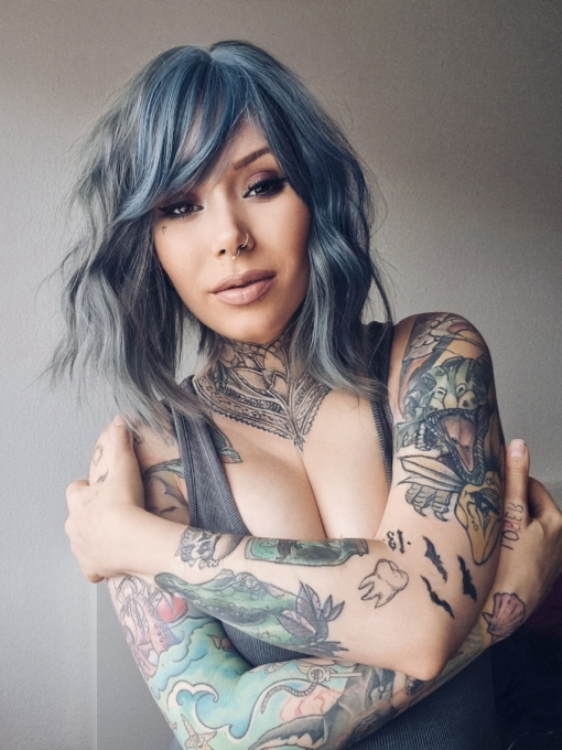 This long bob styled into flat iron waves comes in a mix of dark green and denim blue. Resulting in a wash out effect on colour. A block of blue colour frames the face. The fringe is sleek.