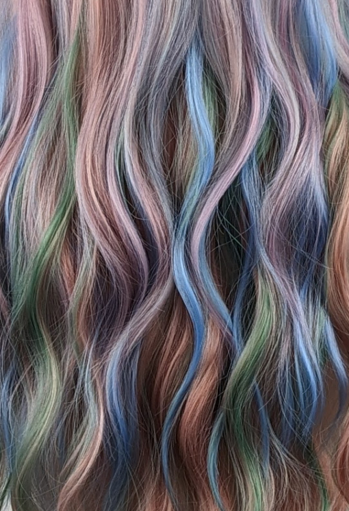 Confetti - Lush Wigs UK Confetti is a mixture of many pastel colours. Peach, lilacs, blues and greens. Long and curly with invisible layers for bounce and a full sleek pink fringe.