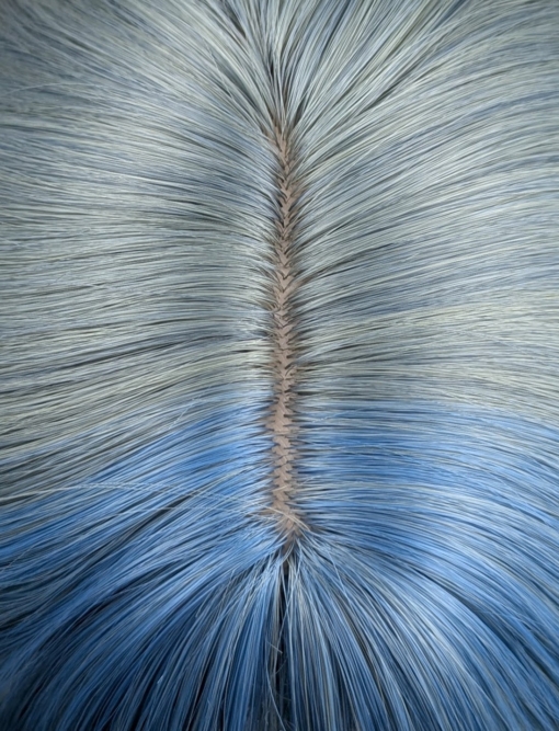 This long bob styled into flat iron waves comes in a mix of dark green and denim blue. Resulting in a wash out effect on colour. A block of blue colour frames the face. The fringe is sleek.