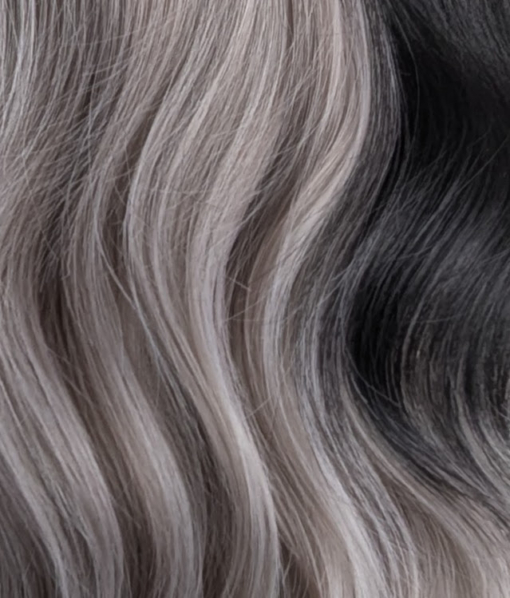 Eclipse - Lush Wigs UK Sterling blonde with a mix of grey. A slice of jet black for added definition takes this style to the next level. Black tones come from the nape of the neck. Giving a peek-a-boo effect. Loose waves fall just past the shoulders, a blunt sleek fringe carries the split colour.