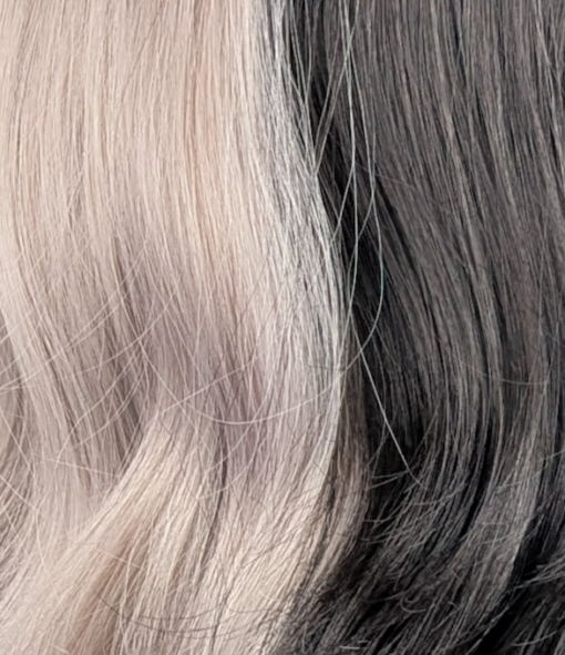Eclipse - Lush Wigs UK Sterling blonde with a mix of grey. A slice of jet black for added definition takes this style to the next level. Black tones come from the nape of the neck. Giving a peek-a-boo effect. Loose waves fall just past the shoulders, a blunt sleek fringe carries the split colour.