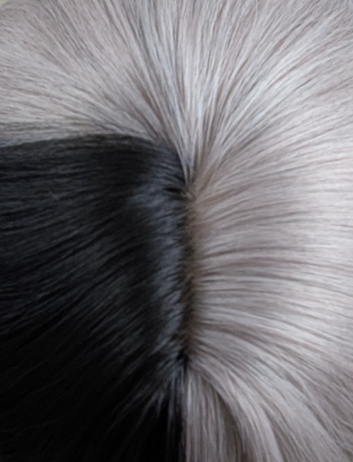 Eclipse - Lush Wigs UK Sterling blonde with a mix of grey. A slice of jet black for added definition takes this style to the next level. Black tones come from the nape of the neck. Giving a peek-a-boo effect. Loose waves fall just past the shoulders, a blunt sleek fringe carries the split colour.