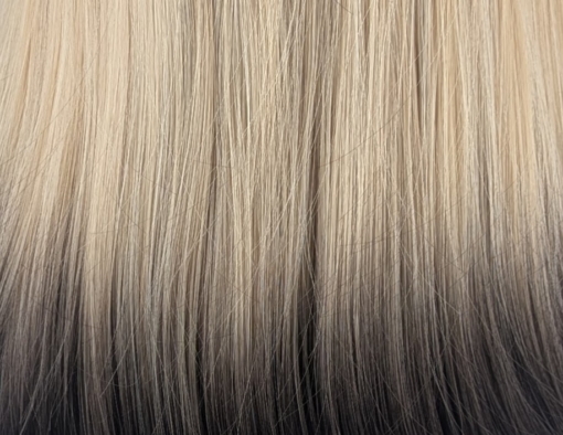 This natural wig is simple but its twist on colour adds some dimension. A sleek long bob (lob) with a light blunt fringe. Dark brown shadowed roots blend into this light blonde colour, finished with a block of dark brown at the tips. A natural mix of colour that sets this look.