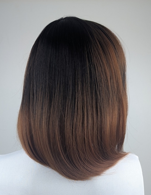 Lucia is a sleek bob that curls under at the ends. Falling to the jawline. This black/brown colour has highlights of copper tones that bring it to life. With a sleek full blunt fringe.
