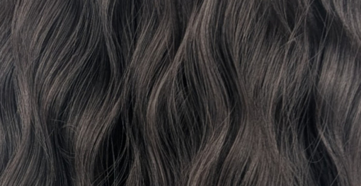 This natural medium length wig comes in a very dark mix of black and a deep brown cocoa tone. From roots to tips. Styled in loose tousled waves with layers and a blunt sleek fringe.