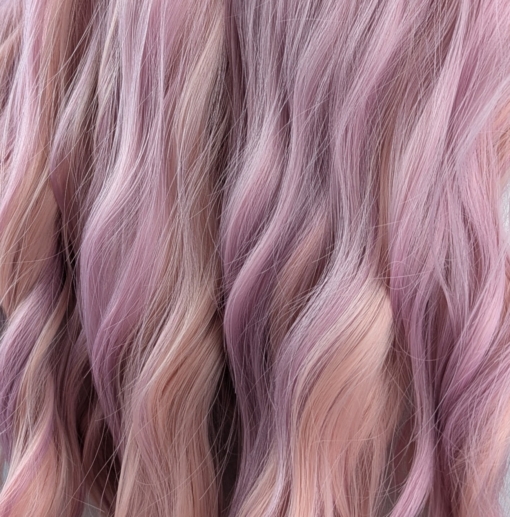 This long style comes in three shades of pastel lilac and peachy pink. Styled into waves. Blonde roots give a natural feel to the style finished with a sleek blunt blonde fringe.