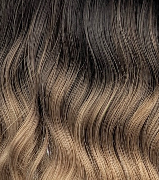 A fringeless A-line bob styled in a loose wave. Warm brown tones from the roots, blend into a dark blonde tint on ends of the hair. A fresh natural look that is casual and easy to maintain.