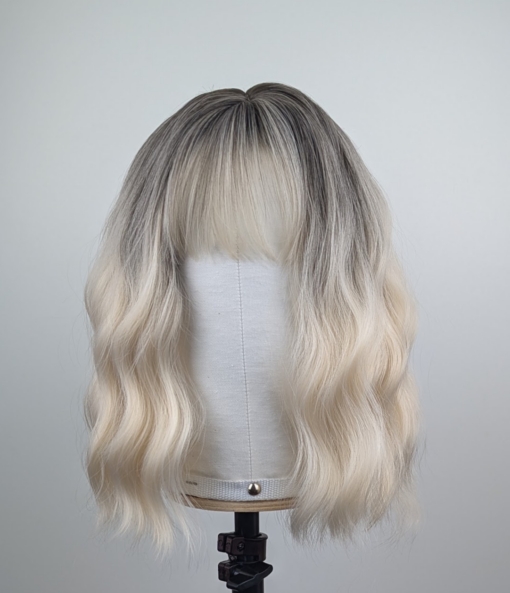 Outlet #149 - Lush Wigs UK A wig with brown shadowed roots that grow into this platinum blonde icy hue. Styled into a bob with loose waves. The fringe is sleek and blunt.