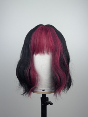 This wavy bob comes to life with a face framing slice of bright purple colour. Thats carried into the sleek fringe and adds a peek-a-boo at the sides. A soft black colour from roots to tips.