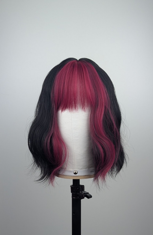 Outlet #236 - Lush Wigs UK This wavy bob comes to life with a face framing slice of bright purple colour. Thats carried into the sleek fringe and adds a peek-a-boo at the sides. A soft black colour from roots to tips.