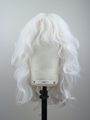 A snow white wig colour from roots to tips. Styled into a loose curl with layers around the face.