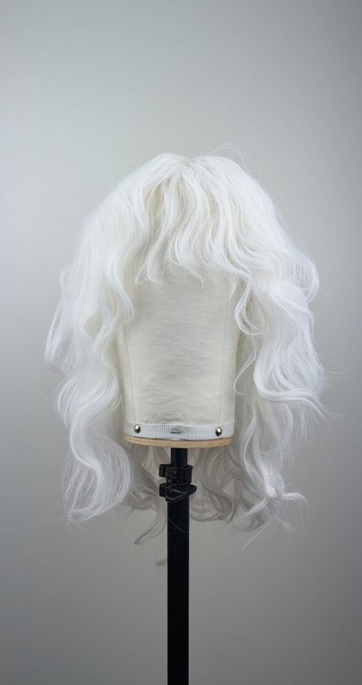 A snow white wig colour from roots to tips. Styled into a loose curl with layers around the face.