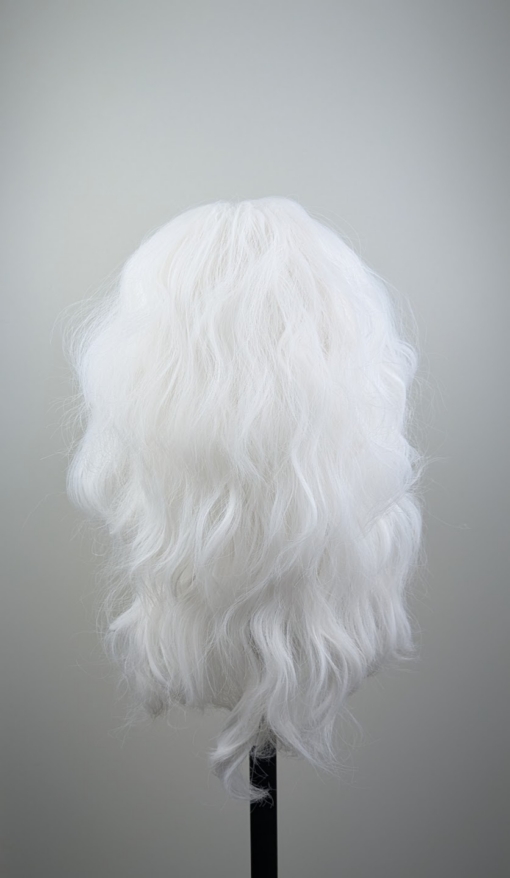 A snow white wig colour from roots to tips. Styled into a loose curl with layers around the face.
