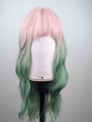 A mix of pastel pink from the roots that melt into a dark green ombre. The style is sleek from the roots with a gentle wave for this one length long style. The fringe is long and sleek that can swept to the side or parted into curtain bangs.