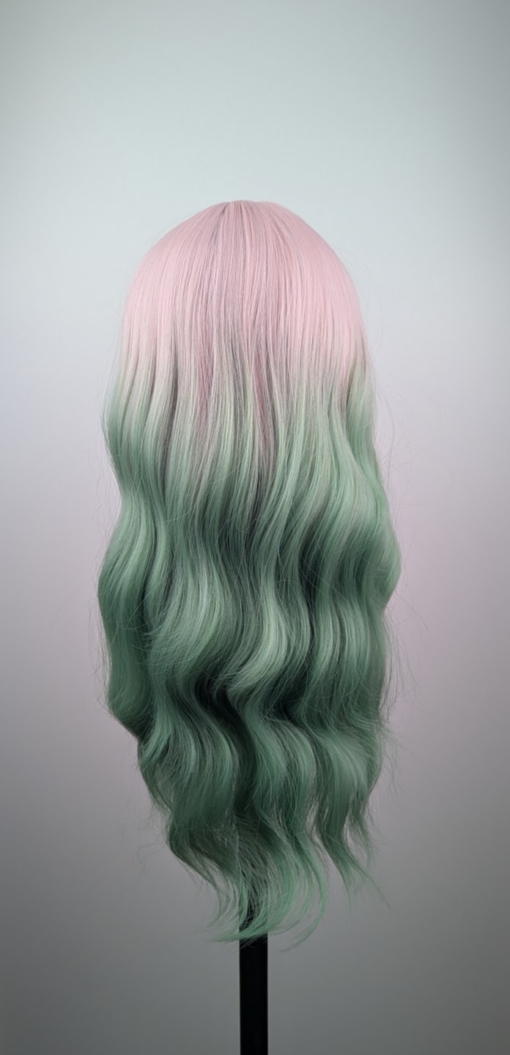 Outlet #239 - Lush Wigs UK A mix of pastel pink from the roots that melt into a dark green ombre. The style is sleek from the roots with a gentle wave for this one length long style. The fringe is long and sleek that can swept to the side or parted into curtain bangs.