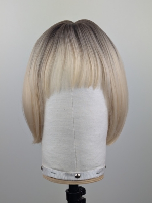 This platinum blonde wig has dark brown shadowed roots for a natural feel. Styled sleek that slightly curls under at the ends. Cut into a jaw skimming bob with a sleek blunt fringe.