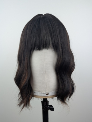 Coffee coloured low-lights, running throughout this very dark brown bob. Styled in gentle waves with a sleek blunt fringe.